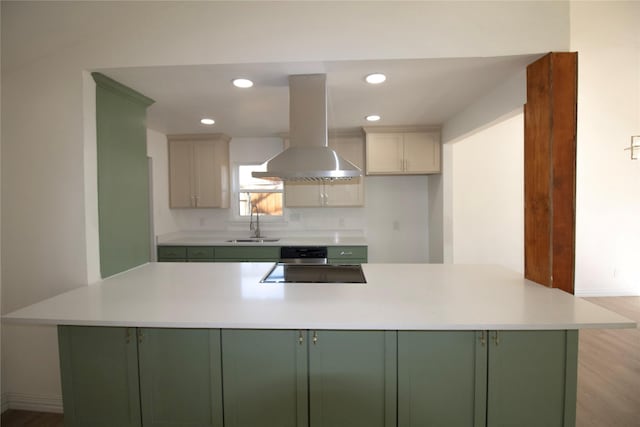 kitchen with island range hood, cooktop, light countertops, and green cabinets