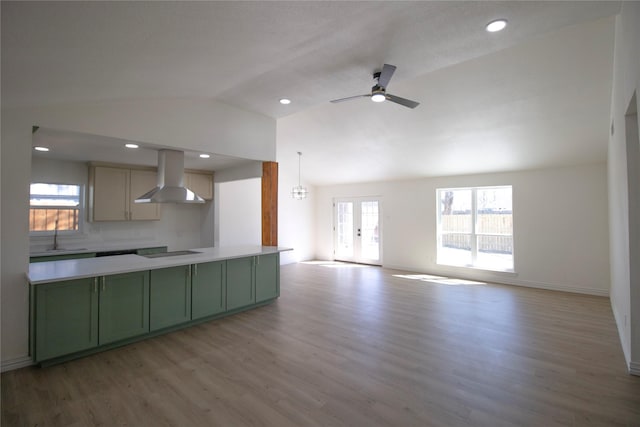 kitchen with light wood-type flooring, a sink, range hood, green cabinets, and lofted ceiling