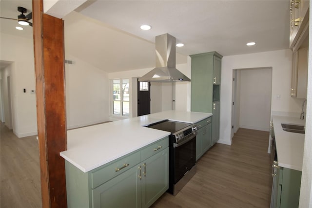 kitchen with green cabinetry, electric range, island range hood, and a sink