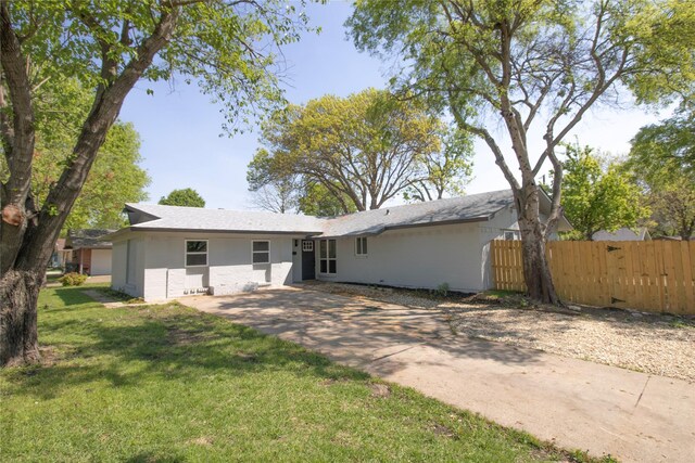 rear view of property featuring stucco siding, driveway, a yard, and fence