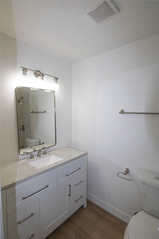 full bathroom with vanity, wood finished floors, visible vents, baseboards, and toilet