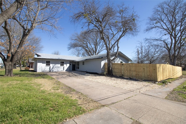 view of front of property with a front yard, concrete driveway, fence, and stucco siding