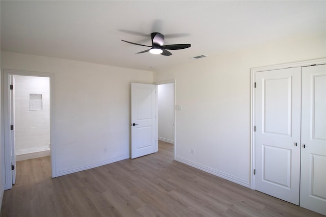 unfurnished bedroom with a closet, a ceiling fan, visible vents, baseboards, and wood finished floors