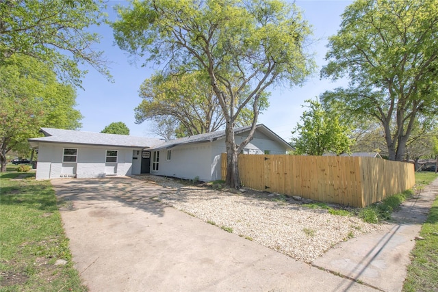view of front of home with fence, concrete driveway, and stucco siding
