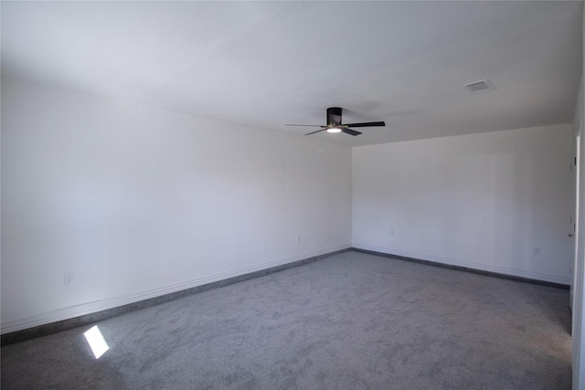 carpeted empty room with visible vents, baseboards, and a ceiling fan