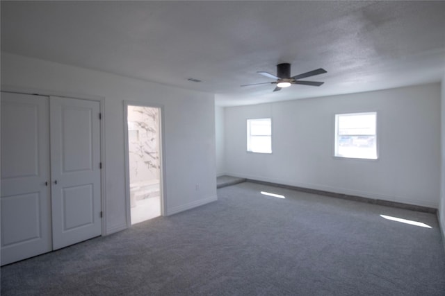 carpeted spare room featuring visible vents, baseboards, and ceiling fan