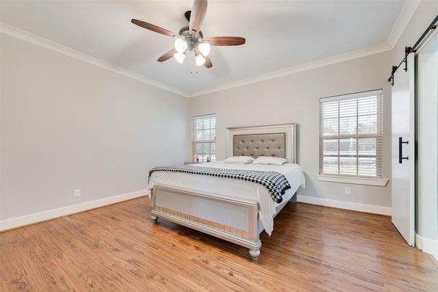 bedroom featuring a barn door, crown molding, and light wood finished floors