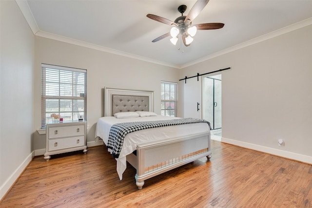 bedroom featuring a barn door, baseboards, light wood-style floors, and ornamental molding