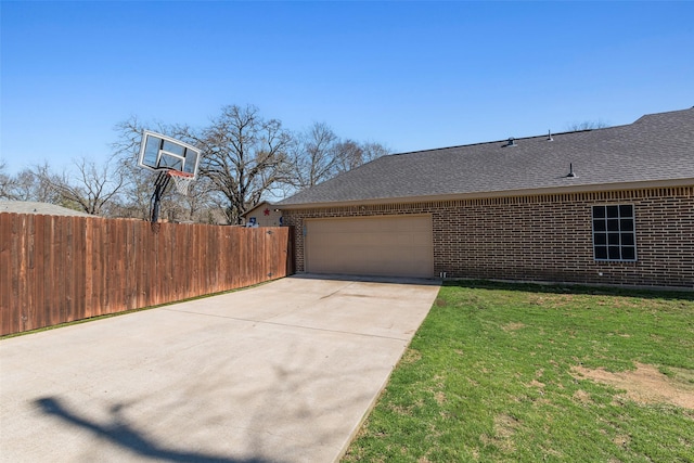 view of side of home featuring brick siding, a lawn, a garage, and fence