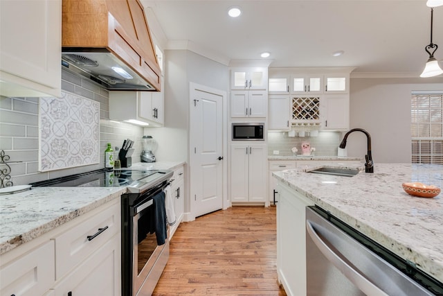 kitchen featuring custom exhaust hood, light wood-style flooring, ornamental molding, a sink, and appliances with stainless steel finishes