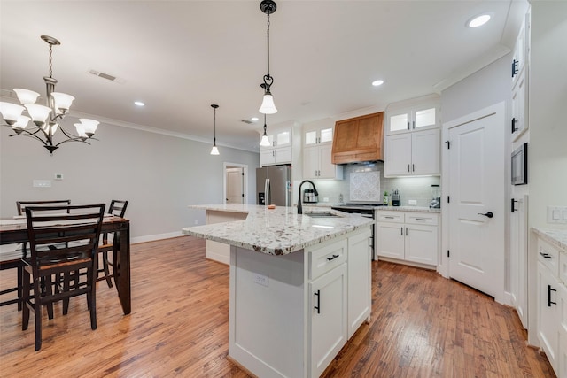 kitchen with visible vents, a sink, ornamental molding, stainless steel refrigerator with ice dispenser, and backsplash