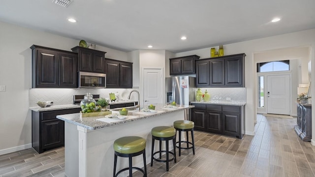 kitchen featuring visible vents, appliances with stainless steel finishes, a breakfast bar area, and wood finish floors