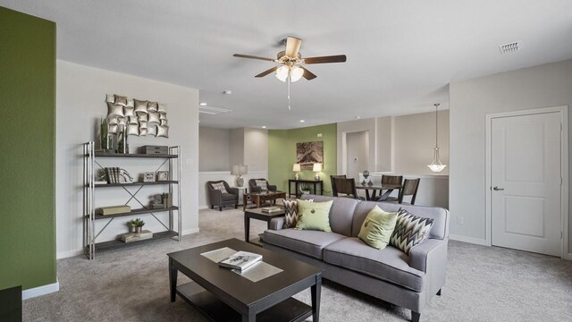 living room featuring a ceiling fan, visible vents, carpet floors, and baseboards