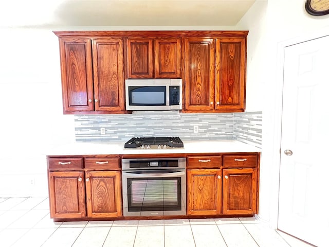 kitchen featuring light tile patterned flooring, backsplash, stainless steel appliances, and light countertops