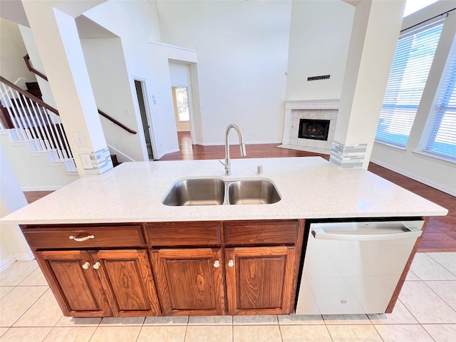 kitchen featuring dishwasher, light stone counters, open floor plan, and a sink