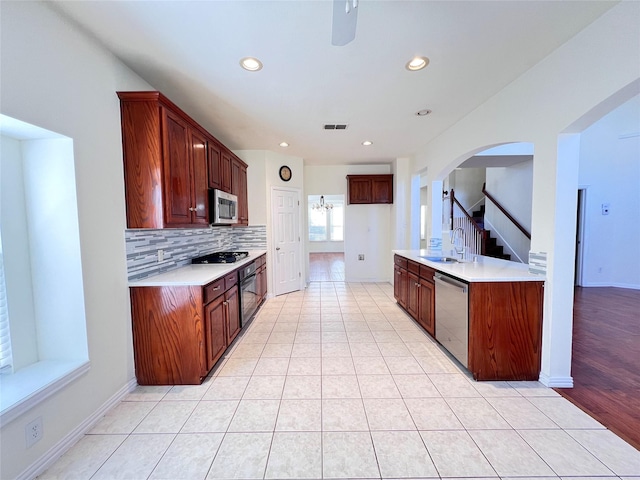 kitchen featuring light countertops, tasteful backsplash, appliances with stainless steel finishes, and a sink