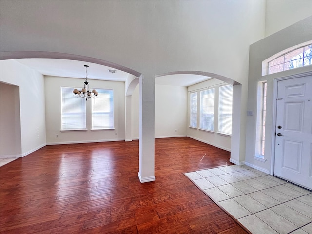 entryway with visible vents, plenty of natural light, a notable chandelier, and wood finished floors