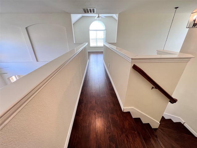 corridor featuring visible vents, baseboards, dark wood finished floors, lofted ceiling, and an upstairs landing