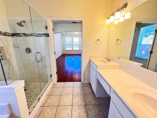 bathroom with tile patterned floors, a stall shower, double vanity, and a sink