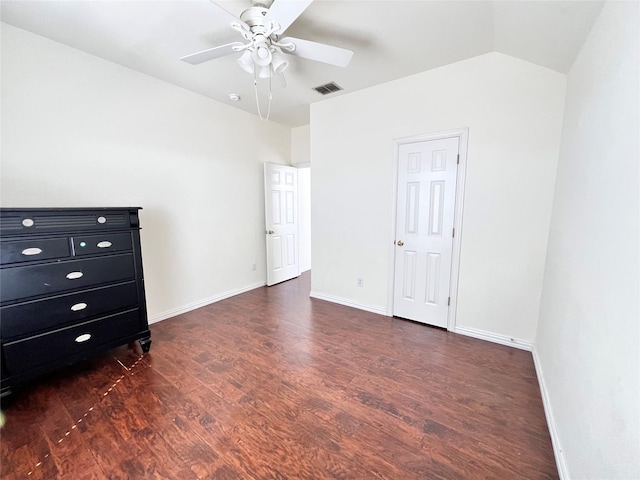 unfurnished bedroom with visible vents, lofted ceiling, baseboards, and dark wood-style flooring