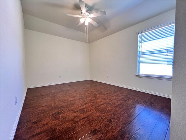 empty room with wood finished floors, baseboards, visible vents, ceiling fan, and vaulted ceiling