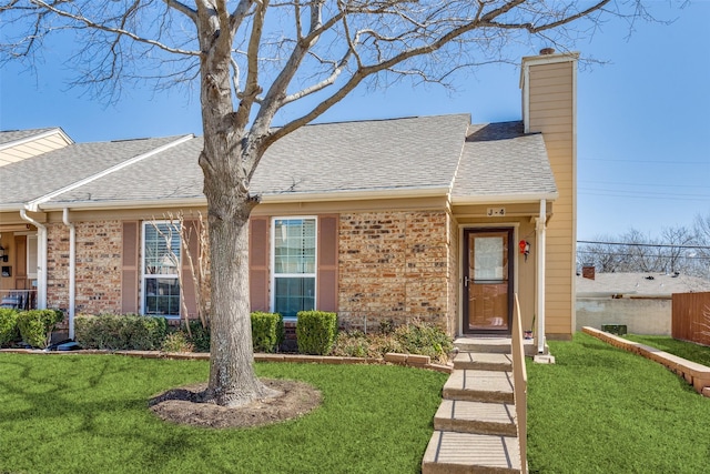 view of front of home featuring a front lawn, brick siding, and a chimney