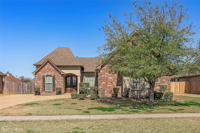 view of front of property with french doors, brick siding, and fence