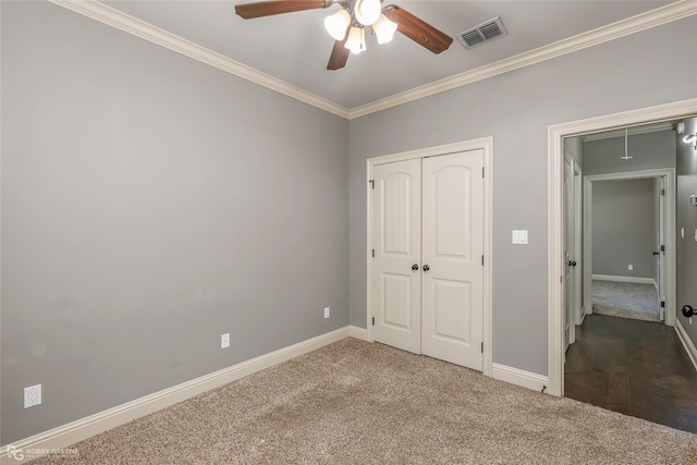 unfurnished bedroom featuring visible vents, crown molding, baseboards, attic access, and carpet flooring