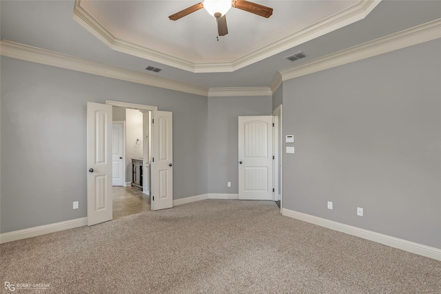 empty room with a tray ceiling, visible vents, and carpet flooring