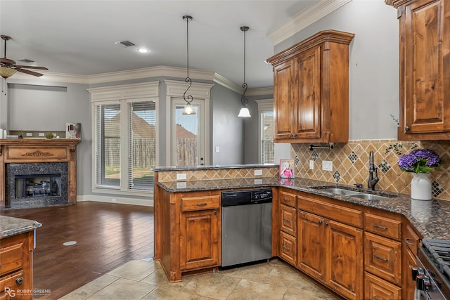 kitchen featuring visible vents, brown cabinets, a fireplace, stainless steel dishwasher, and a sink