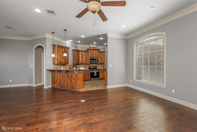 kitchen with visible vents, stainless steel appliances, arched walkways, a peninsula, and brown cabinetry