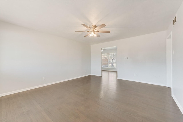 empty room featuring dark wood-type flooring, baseboards, visible vents, and ceiling fan