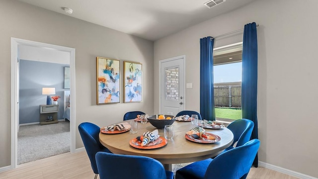 dining area with visible vents, light wood-type flooring, and baseboards