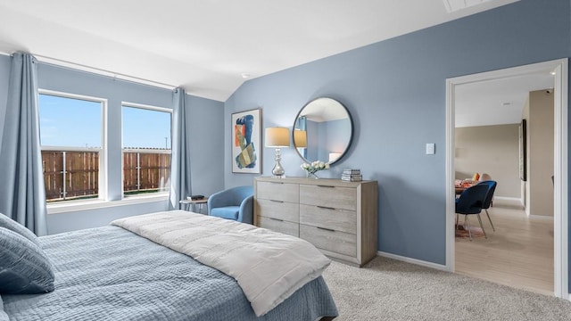 bedroom with light carpet, baseboards, and vaulted ceiling