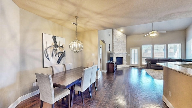 dining area featuring baseboards, a large fireplace, dark wood finished floors, and vaulted ceiling