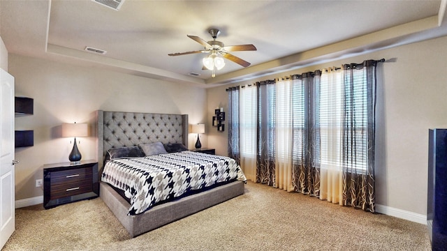 bedroom with light carpet, visible vents, baseboards, and a tray ceiling