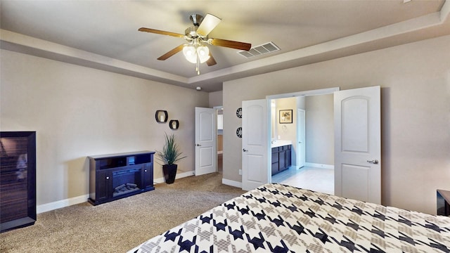 bedroom featuring a tray ceiling, light colored carpet, visible vents, and baseboards