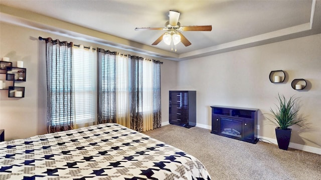 bedroom with a tray ceiling, baseboards, and carpet