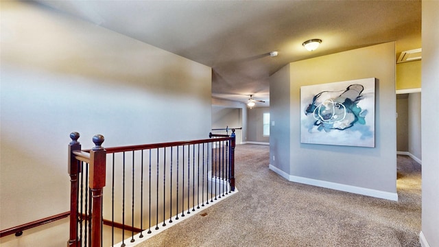 hallway featuring baseboards, an upstairs landing, and carpet