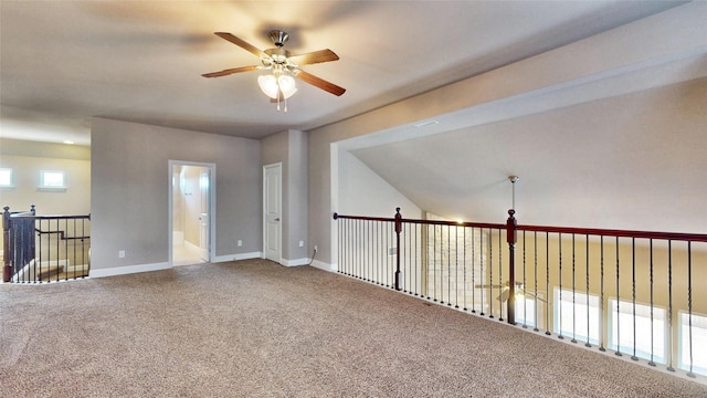 carpeted empty room with a ceiling fan and baseboards