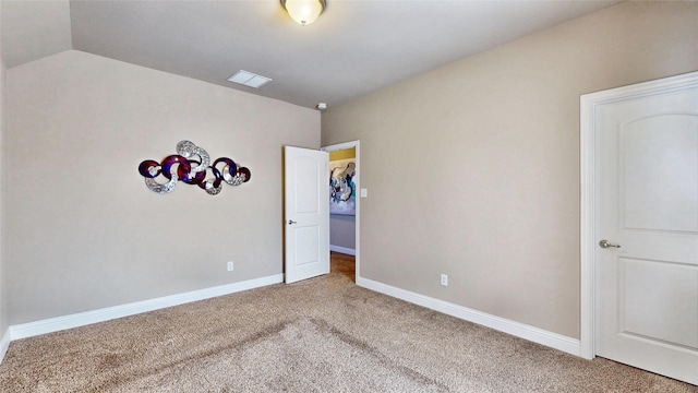 unfurnished bedroom featuring vaulted ceiling, carpet flooring, baseboards, and visible vents