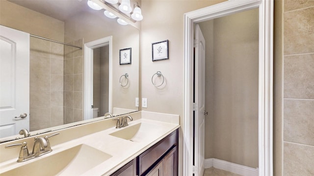 bathroom with a sink, baseboards, toilet, and double vanity