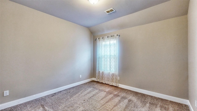 empty room featuring visible vents, baseboards, lofted ceiling, and carpet