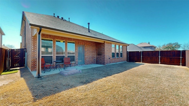 rear view of property featuring a patio, a fenced backyard, brick siding, and a shingled roof