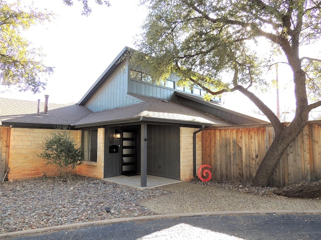 view of front of home with roof with shingles and fence