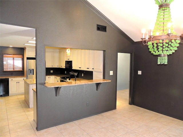 kitchen featuring visible vents, ornamental molding, black appliances, cream cabinetry, and a kitchen breakfast bar