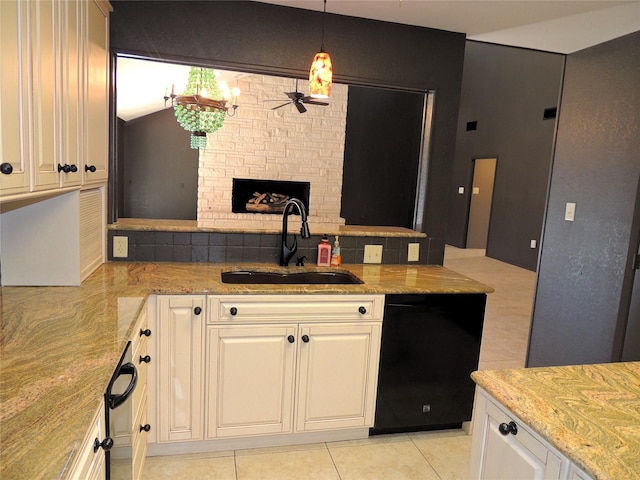 kitchen featuring a sink, light stone counters, black dishwasher, a peninsula, and a fireplace