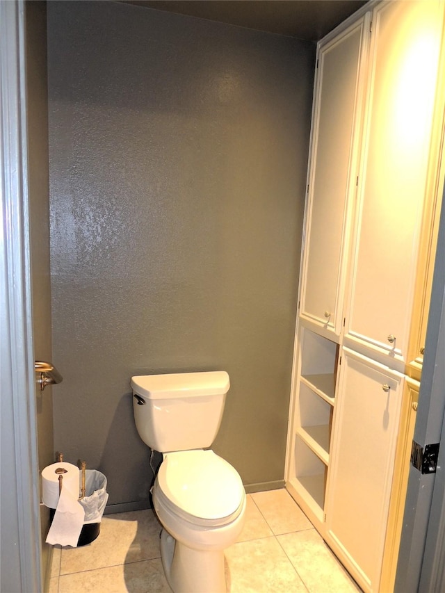 bathroom with tile patterned flooring, toilet, and baseboards