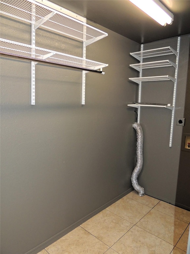 clothes washing area featuring baseboards, light tile patterned floors, laundry area, hookup for a washing machine, and electric dryer hookup