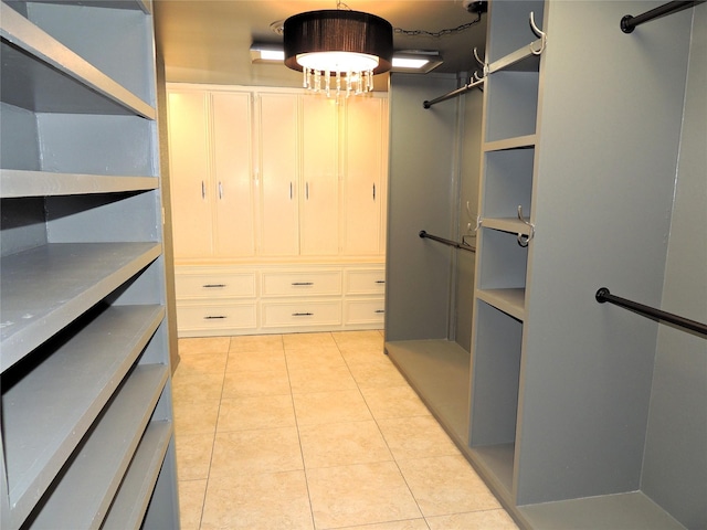 walk in closet with light tile patterned floors and a chandelier